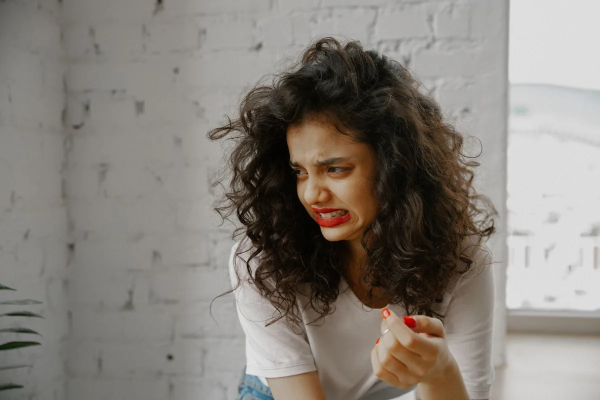 A woman with curly hair showing a disgusted facial expression.