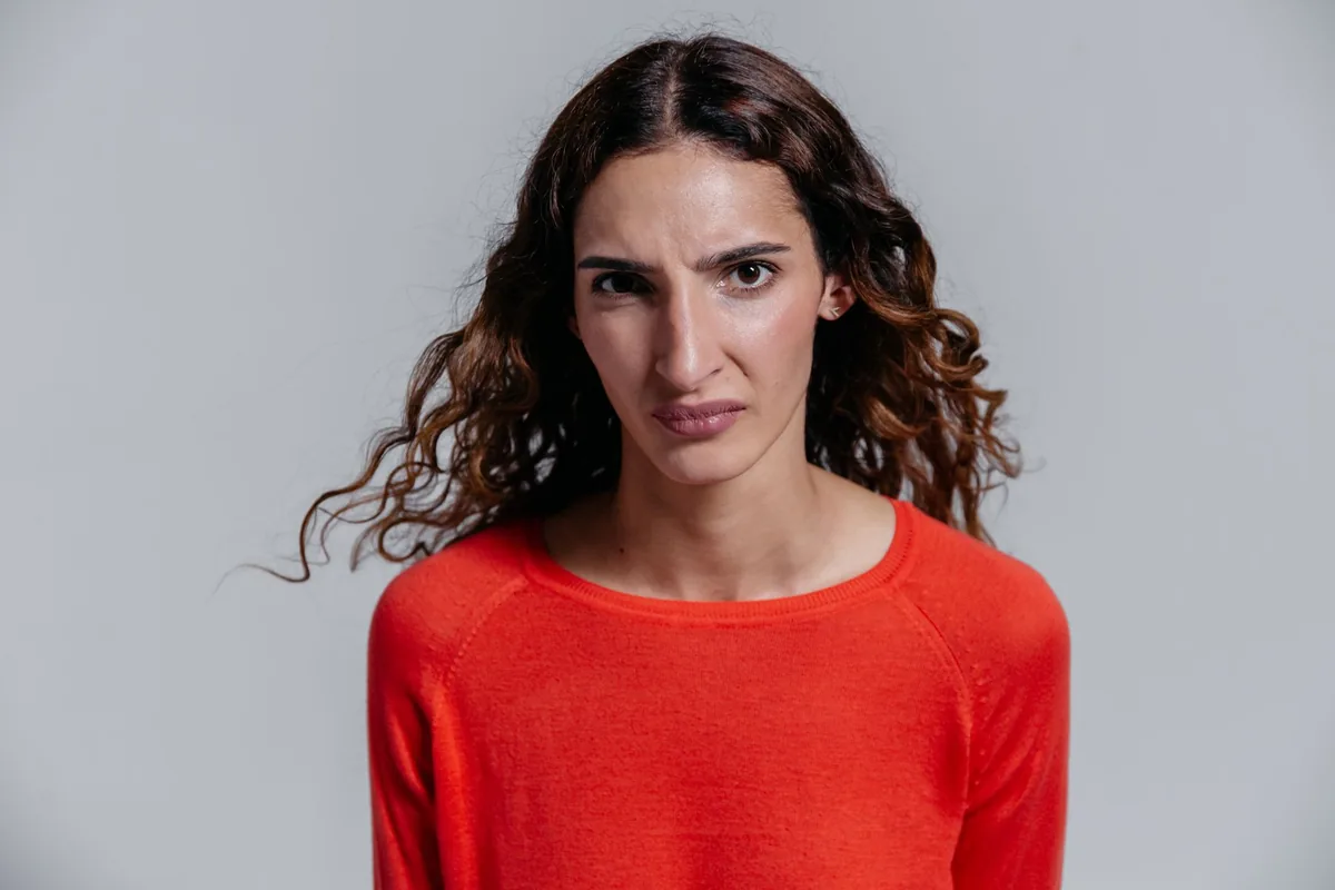 A woman in a red sweater with a disgusted facial expression.