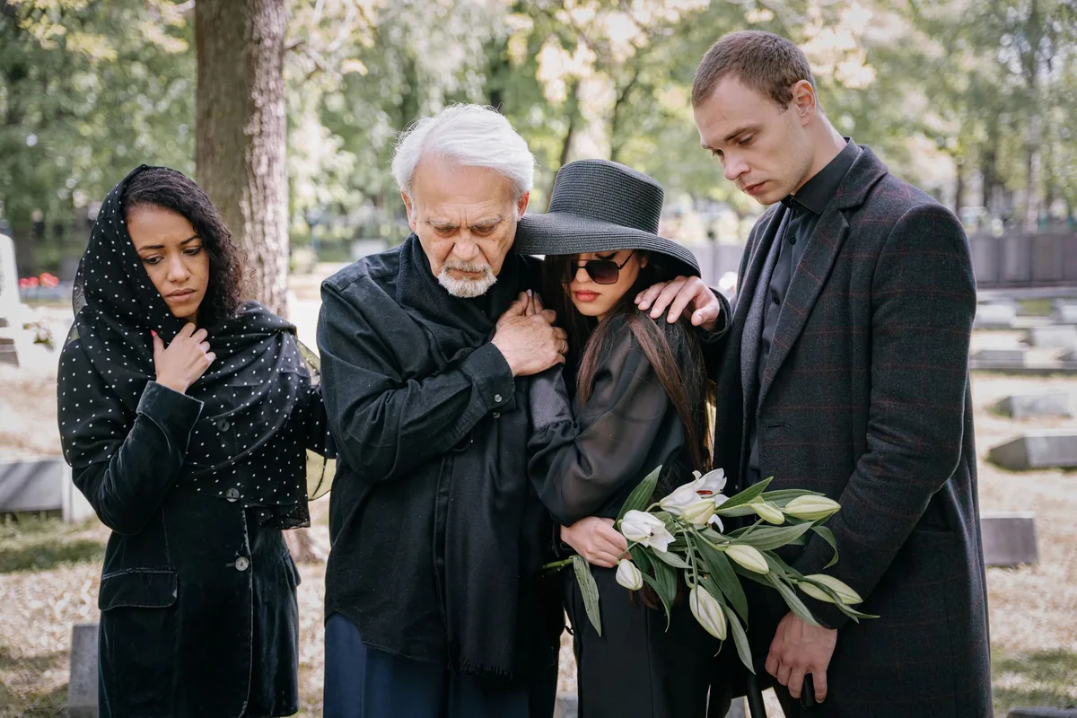 A family grieving and supporting one another at a cemetery.