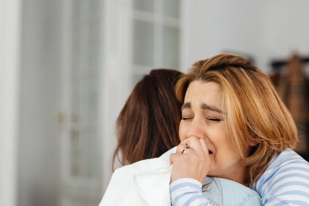 Two women embracing for comfort in a moment of sadness.