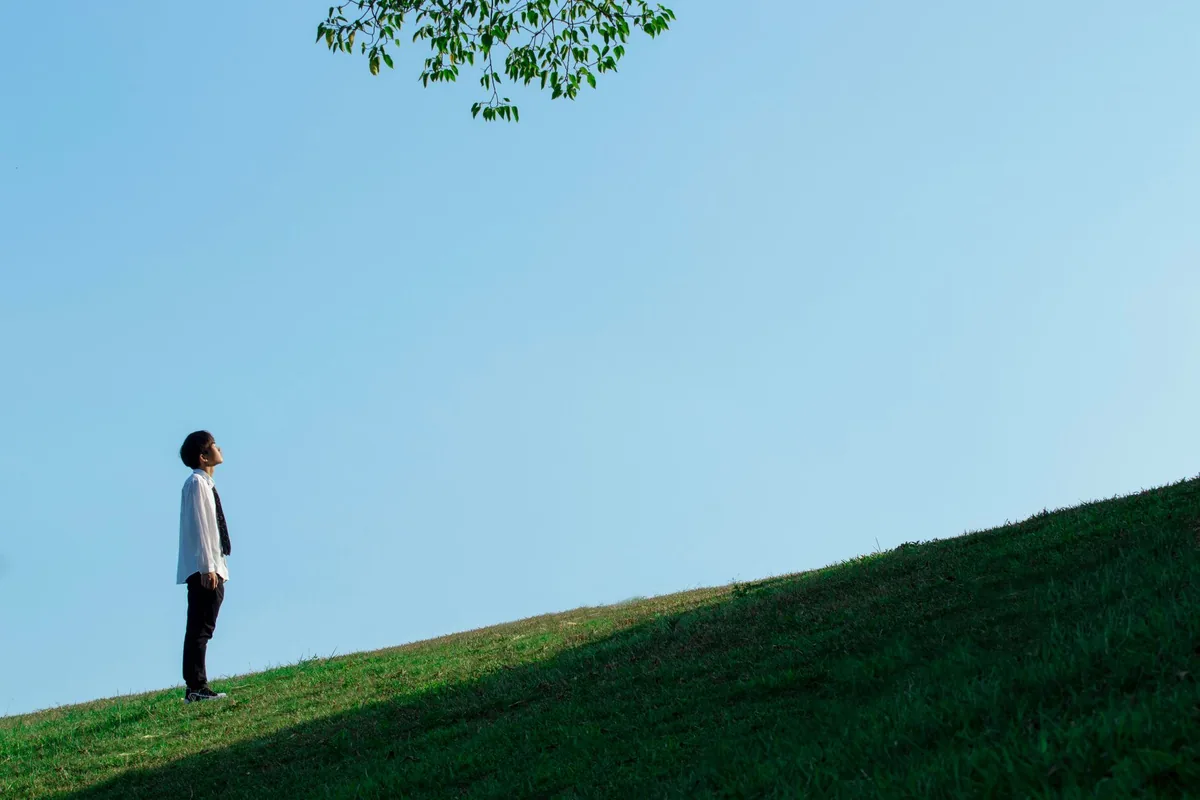 A person looking up toward the sky on a hill.
