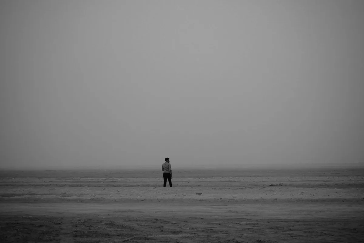 A lone man standing on an empty beach.