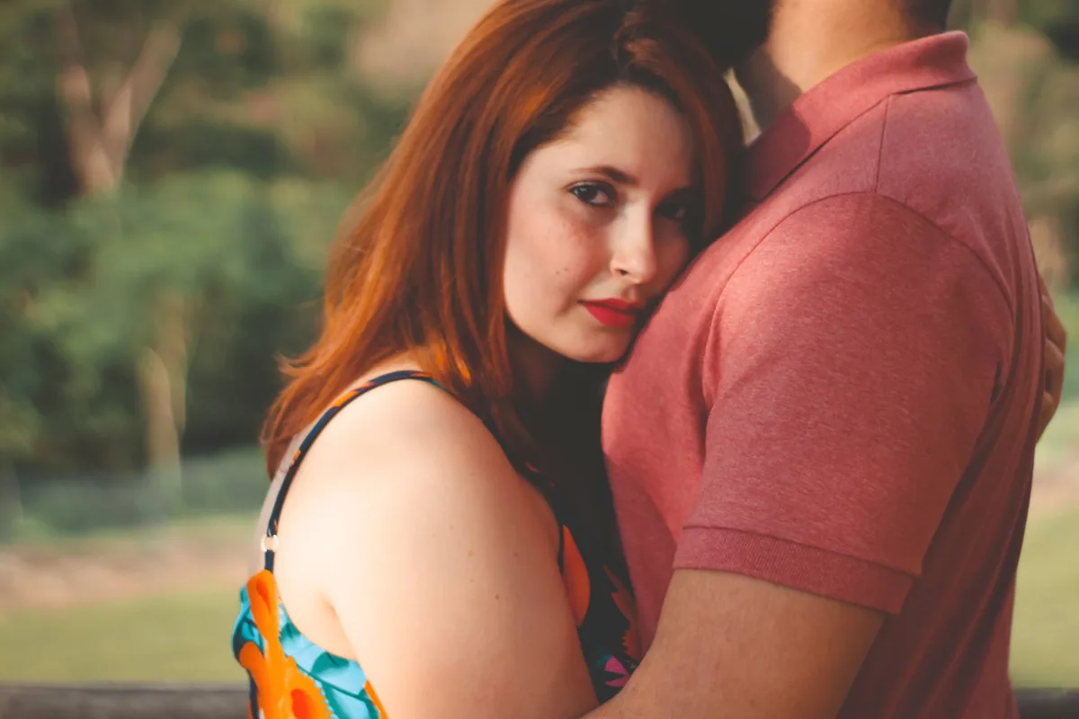 A couple embracing in a sunny outdoor setting.