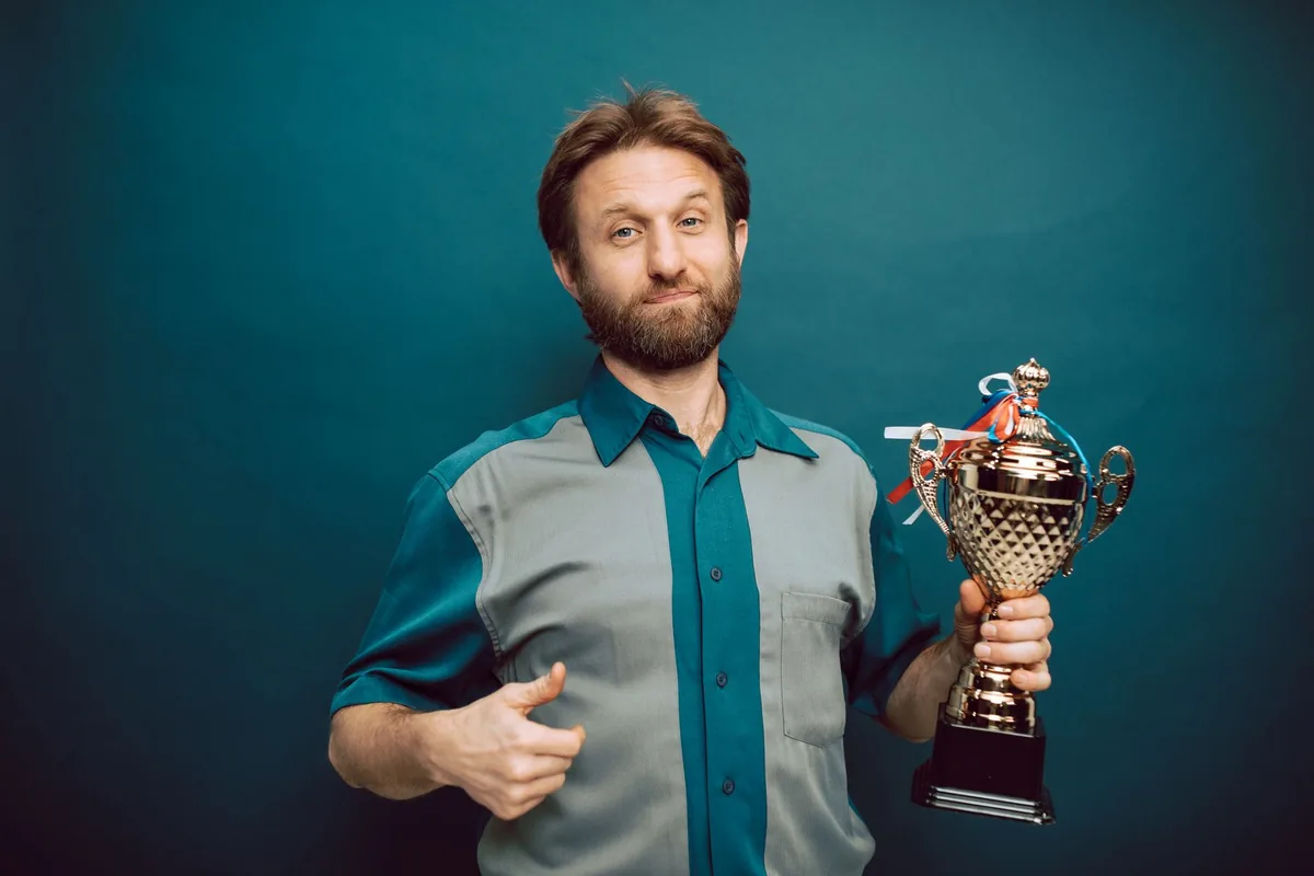 A man holding a trophy, showing pride in an accomplishment.